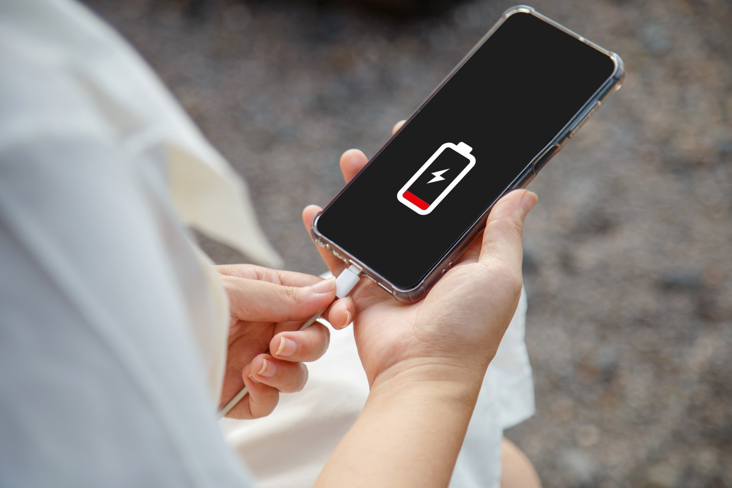 mujer carga un smartphone con baja bateria en la calle